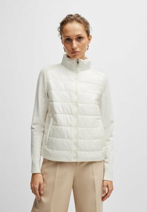 Leichte Steppweste in Off-White mit hohem Kragen, gestepptem Vorderteil und weichen Ärmeln. Verfügt über einen durchgehenden Reißverschluss und eine taillierte Silhouette.