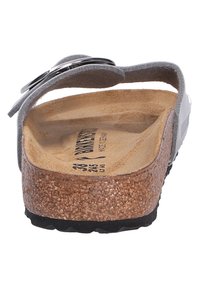 Sandale en gris avec un pied en liège, un dessus en daim doux et un accent en boucle métallique réglable. Semelle extérieure en caoutchouc noir pour une meilleure adhérence.