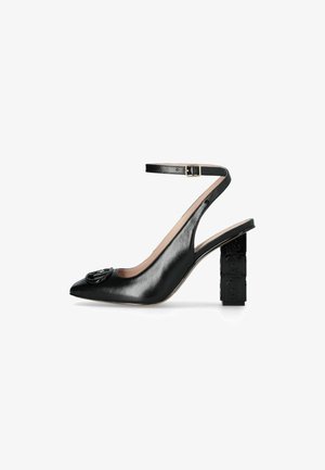 Scarpa slingback in pelle nera con punta affusolata, caratterizzata da un tacco blocco testurizzato e un accento decorativo con logo sulla punta.