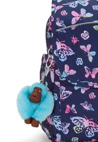 Mörkblå ryggsäck med ett fjärilsmönster i rosa och ljusblått. Innehåller en fluffig turkossfärgad nyckelring i form av en apa.