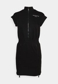Robe noire à manches courtes zippée avec col montant, taille élastique, deux fermetures éclair verticales sur la jupe et inscription blanche « Versace Jeans Couture 35 2023 » sur la poitrine.