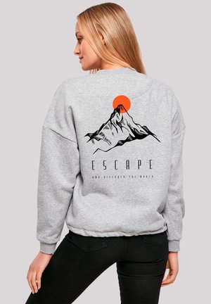 Gray sweatshirt featuring a mountain graphic with an orange sun. Text below reads "ESCAPE AND DISCOVER THE WORLD." Casual fit, soft texture.