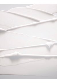 Crema o lozione bianca liscia stesa uniformemente con dolci creste e trame su una superficie piana.