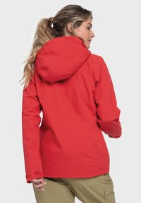 Giacca impermeabile rossa con cappuccio, texture liscia, polsini elastici e orlo regolabile. Presenta un design minimal e snello.