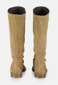 Botas de ante color beige hasta la rodilla con una textura suave, que presentan una punta redondeada y un tacón bajo en bloque. El interior está forrado en cuero negro.