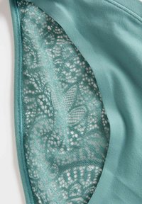 Petrolblauwe stof met een gladde textuur en verfijnde kantdetails in een bloemmotief aan één kant, en een effen petrolblauwe achterkant aan de andere kant.