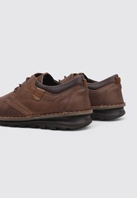Chaussures en cuir marron avec des panneaux texturés, semelle légère et lacets foncés contrastants. Conçues pour le confort avec un style décontracté.