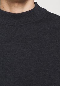 Dunkelgrauer Rollkragenpullover mit gerippter Textur und figurbetontem Design, das einen hohen Ausschnitt und einen durchgehend glatten Stoff zeigt.