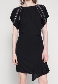 Black dress with short, draped sleeves. Features rhinestone accents along the shoulders, a fitted waist, and a wrap-style skirt.