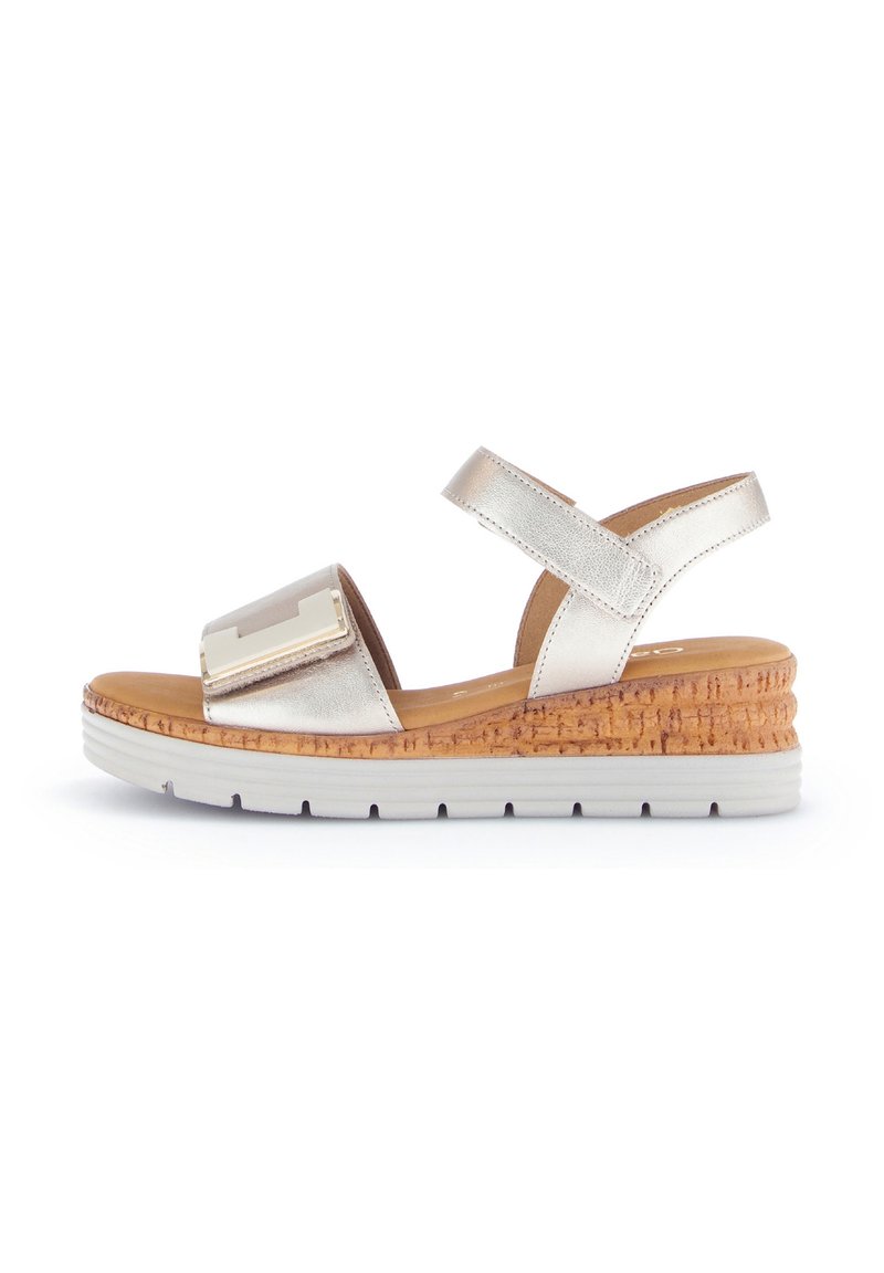 Metallisch goldene Keilsandalen mit Korkbasis, breitem Riemen mit dekorativem Hardware-Akzent und verstellbarem Knöchelriemen.