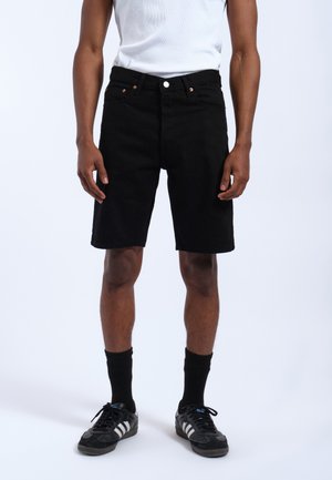Black denim shorts with a regular fit, featuring a button and zipper closure, front pockets, and a smooth texture, worn with black athletic socks and shoes.