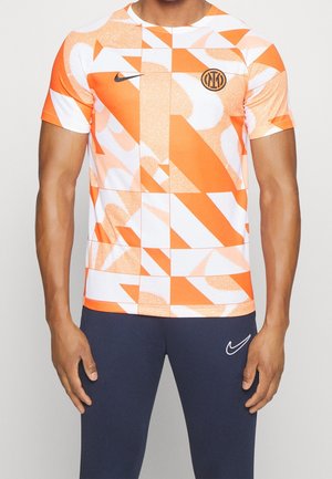 T-shirt Nike orange et blanc avec des motifs géométriques, manches courtes, col rond et logo sur la poitrine. Fabriqué en tissu léger.