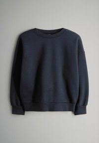 Tummansininen pitkähihaine crewneck collegepaita, jossa on ribbaus (kudontapitsi) hihoissa ja helmassa, esitettynä vaaleanharmaata taustaa vasten.