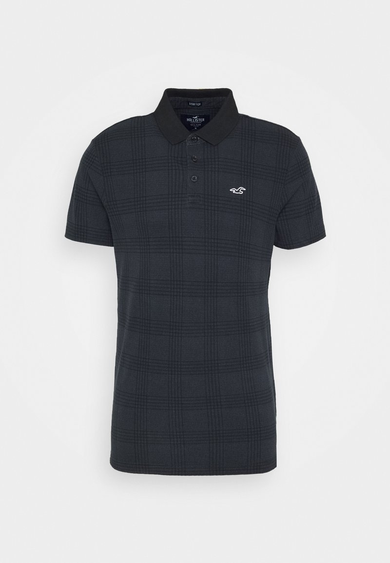 Camisa polo de cuadros negros hecha de tejido texturizado, con cuello, tapeta de dos botones y un pequeño logotipo blanco en el pecho.