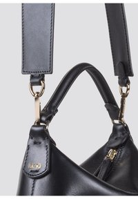 Zwarte leren handtas met een gebogen vorm, voorzien van gouden hardware, een afneembare schouderband en zichtbare stiksels.