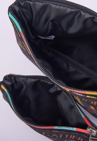 Mehrere Fächer Tasche aus schwarzem Stoff. Verfügt über Reißverschlüsse, bunte Stoffakzente und eine glatte Innenstruktur.