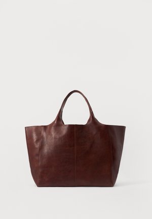 Sac fourre-tout en cuir brun avec une texture lisse, un corps large et deux poignées courtes. Présente des coutures minimalistes, sans quincaillerie ou accents visibles.