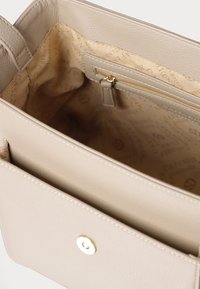 Borsa a mano in pelle beige con superficie texturizzata. L'interno presenta una fodera in tessuto chiaro e una tasca con zip, oltre a due scomparti aperti.