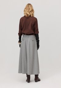 Brązowa koszula z długim rękawem, szara spódnica w kant, czarne rękawiczki, ciemnobrązowe botki. Gładki materiał, klasyczny krój, spódnica do kostek z tylnymi kieszeniami.