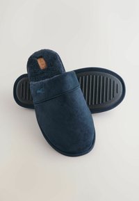 Navy blue slippers made of soft plush material, featuring a cushioned interior and rubber sole with ridges for grip. Light logo detail visible.