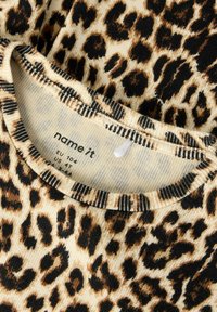 Leopardi mustriga kangas soonilise tekstuuriga. Kaelusega, musta ja tan värvikombinatsiooniga, nähtava brändisildiga.