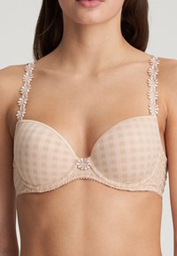 Vaalea beige rintaliivi, jossa on ruudullinen kuvio, kukkaviehe hihnoissa ja koristeellinen kukka yksityiskohtana keskellä. Sileä pinta, tuettu malli.