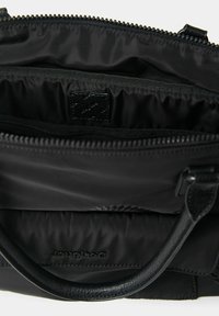 Borsa nera con cerniera aperta che mostra i compartimenti interni e una maniglia in pelle, con cuciture di marca all'interno.