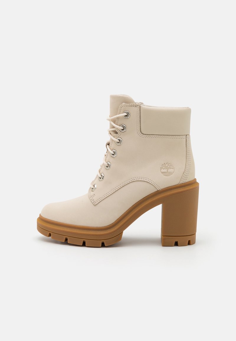 Bottine beige en cuir avec talon marron chunky, lacets à l'avant, col rembourré et logo arbre embossé sur le côté.