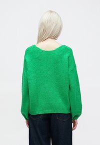 Πράσινο πλεκτό πουλόβερ με χαλαρή εφαρμογή, φαρδιά μανίκια και φαρδιά λαιμόκοψη. Υφή νήματος και ριμπ μανσέτες και στρίφωμα.