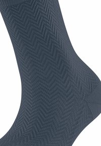Chaussettes bleu foncé avec un motif chevron texturé, fabriquées à partir d'un matériau doux et extensible. Le design montre un gros plan du tissage du tissu.