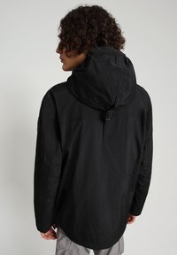 Schwarze leichte Jacke mit Kapuze, verstellbarem Kordelzug und Seitentaschen; verfügt über ein mattes Finish und ein locker sitzendes Design.