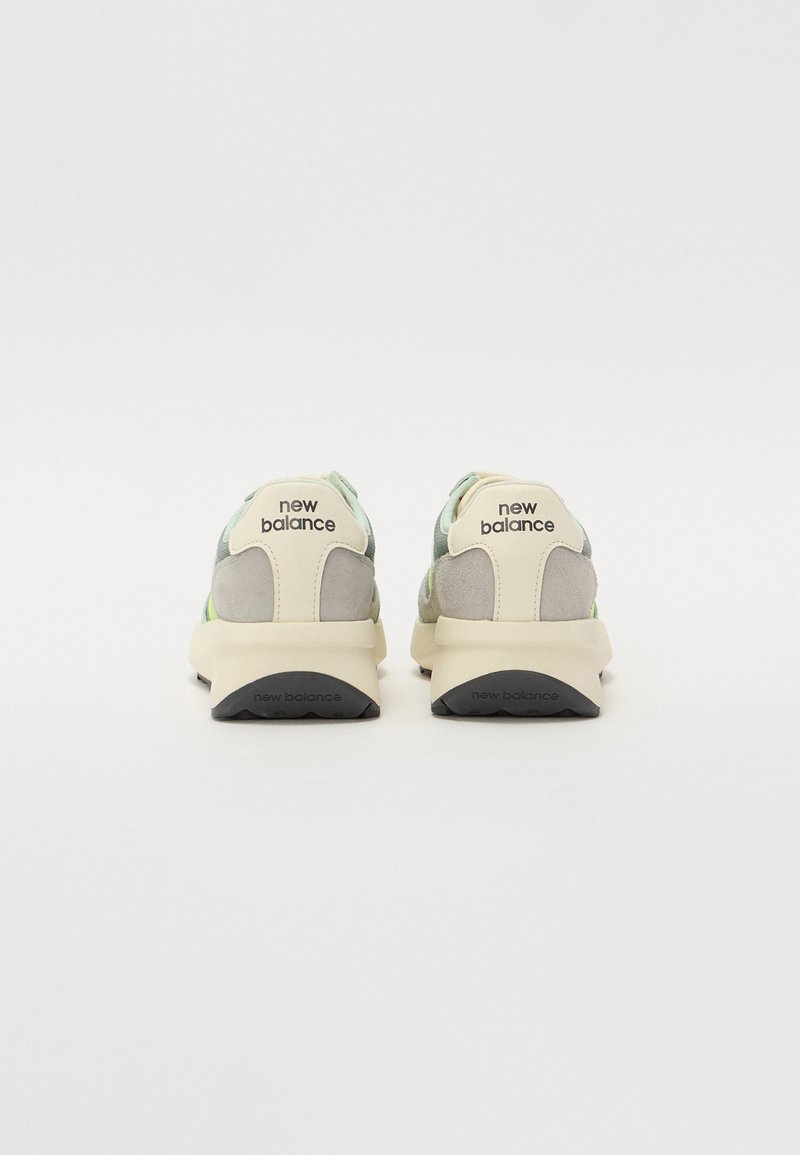 New Balance Sneakers mit einer Mischung aus grauem und grünem Wildleder, einer gepolsterten Sohle und einem auffälligen Logo auf der Ferse. Glatte Textur.