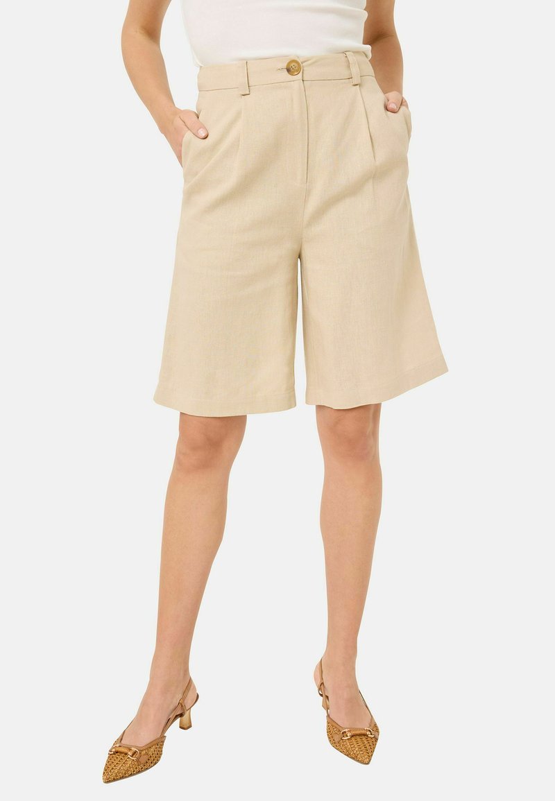 Beige skræddersyede shorts med plisseringer, lommer og knaplukning. Stoffet virker glat med en let tekstur og en afslappet pasform.