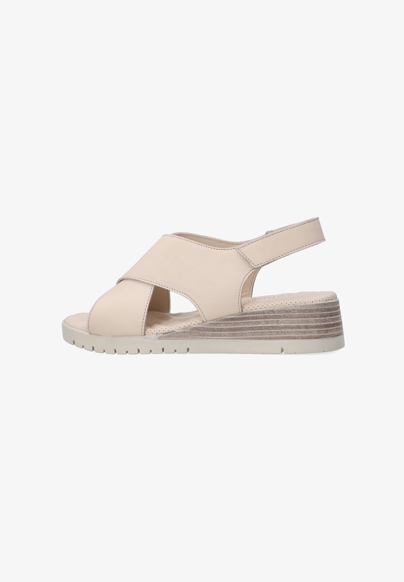 Beige wedge sandals with cross-strap design, open toe, and back strap. Textured wedged sole with horizontal lines. Soft material finish.