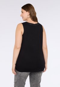 Svart ärmlös topp i mjukt material, med rund halsringning och rak passform. Baksidan har en enkel design utan extra dekorationer.