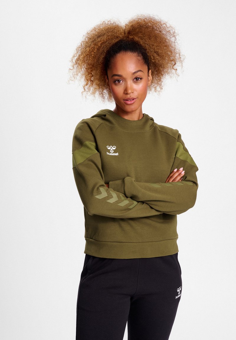 Olive green hooded sweatshirt with a textured finish, featuring a logo on the chest and chevron patterns on the sleeves. Paired with black pants.
