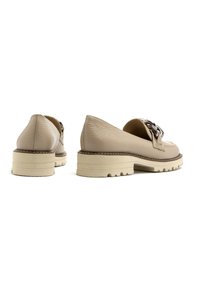 Scarpe in pelle beige con finitura testurizzata, dotate di una suola spessa di colore chiaro e di un accentato decorativo in metallo sulla parte superiore.