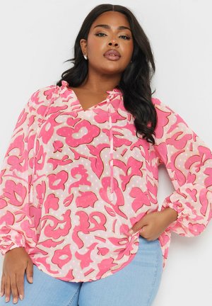 Pink patterned blouse with long sleeves, a v-neckline, and drawstring detail. Features a light, sheer fabric with floral motifs and polka dots.