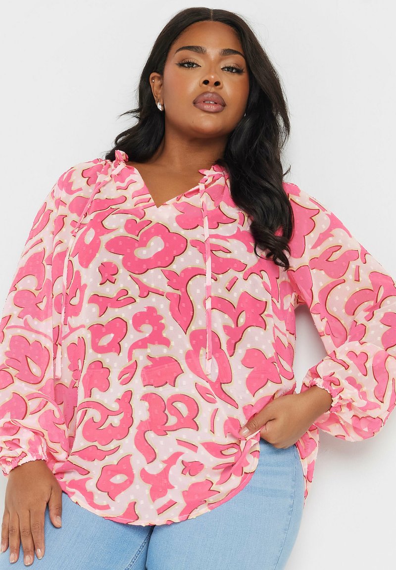 Blusa rosa con fantasia, maniche lunghe, scollatura a V e dettaglio con cordoncino. Caratterizzata da un tessuto leggero e trasparente con motivi floreali e pois.