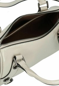 Borsa a mano in pelle crema chiaro con chiusura a zip, dettagli in metallo argentato e un ampio interno marrone. Presenta una texture liscia e una forma ben strutturata.