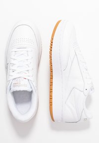 Vita lädersneakers med en slät yta, perforerade detaljer på tån och en gummisula med ett räfflat mönster.