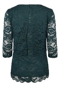 Donkergroene kanten top met lange mouwen, bloemenpatroon, gegolfde zoom en een open rugontwerp. Gestructureerde stof met complexe details.