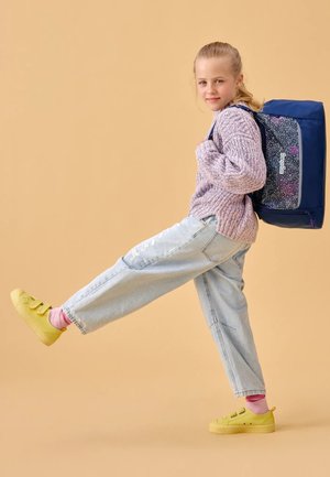 Blue backpack with speckled design, lavender knit sweater, light blue distressed jeans, and yellow sneakers with pink socks.