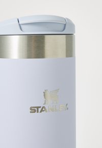 Light blue Stanley travel mug with silver rim and winged lion logo on a white background.