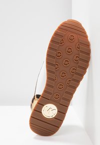 Leopardenmuster-Sneaker mit braunem Gummisohle, ausgestattet mit einem Logo-Akzent und strukturiertem Griffmuster. Obermaterial ist weißes Mesh.