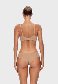 Nude biustonosz i komplet bikini z regulowanymi ramiączkami. Gładka faktura i minimalistyczny design bez widocznych wzorów czy zdobień.