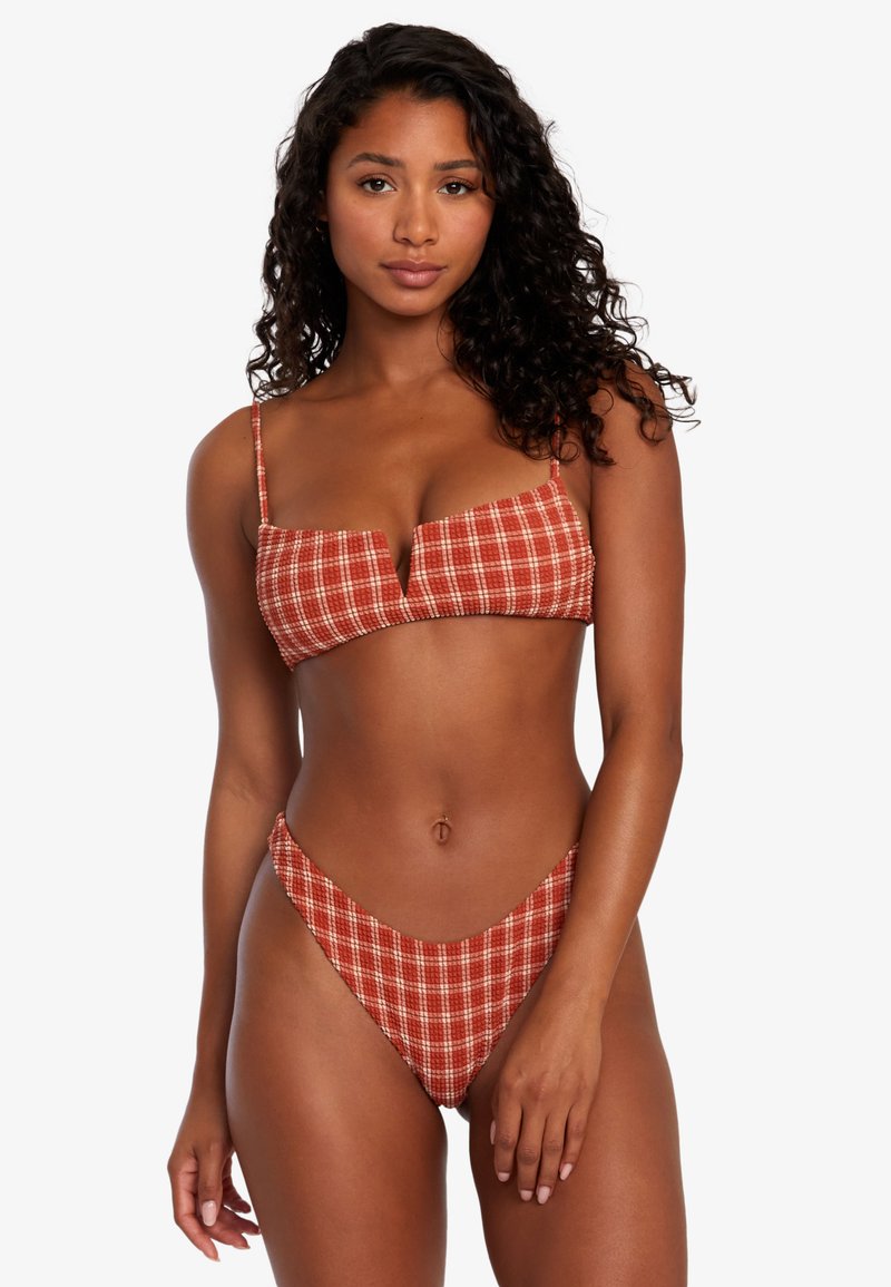 Červeno-biele kockované bikiny so štruktúrovaným vrchom braletového strihu a vysokým strihom na spodnej časti, vyrobené z elastického materiálu. Vyznačujú sa tenkými ramienkami.