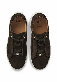 Brązowe zamszowe trampki z białą gumową podeszwą. Posiadają teksturowane sznurowadła i złote elementy ozdobne. Logo widoczne wewnątrz i na języku.