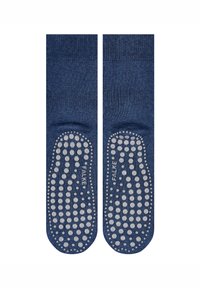 Calcetines de agarre azul marino que cuentan con una superficie texturada con puntos de silicona circulares, puntera y talón reforzados, etiquetados como "Falke" en el lateral.