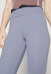 Vaaleanpurppurat legginsit, joissa on sileä ja joustava pinta. Niissä on korkea vyötärö ja litteät saumat sivuilla mukavuutta ja istuvuutta varten.